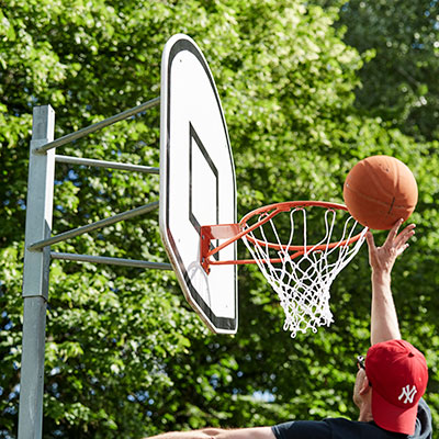 A boy is playing basketball and is about to score a goal in the hoop.